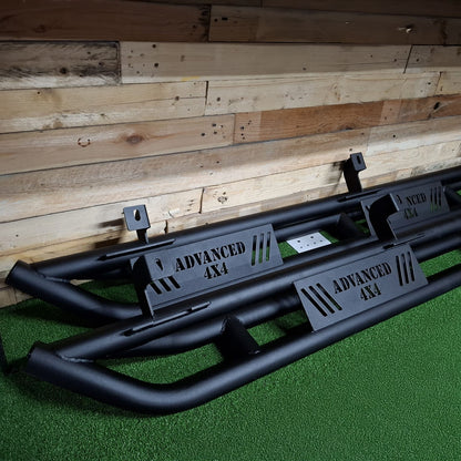 A pair of black steel rock sliders for a Jeep JK 5 Door vehicle, displayed against a wooden backdrop.